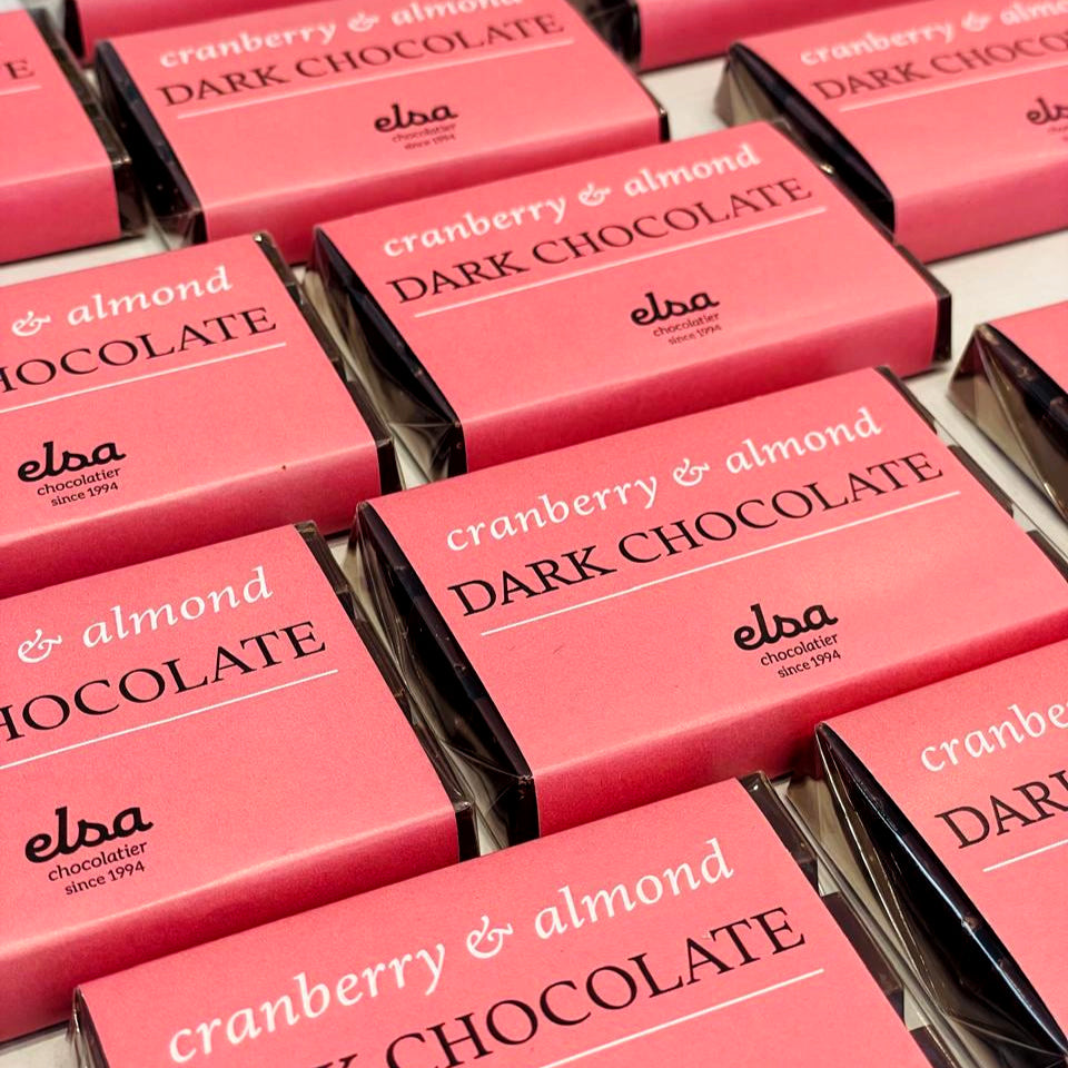 Cranberry and Almond Dark Chocolate Bars in pink wrappers arranged in rows