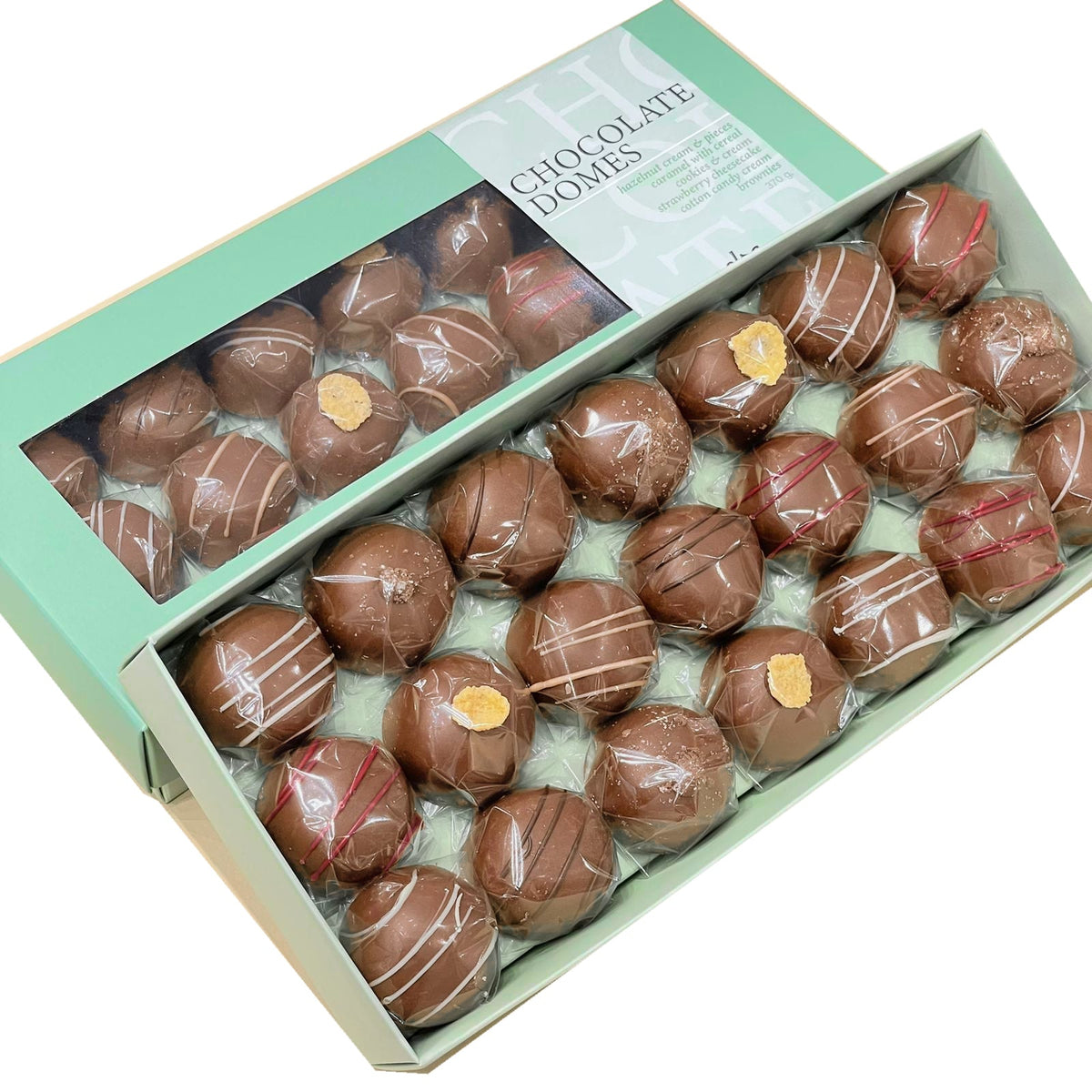 Assorted individually wrapped chocolate domes in an open mint-green box beside matching windowed packaging.