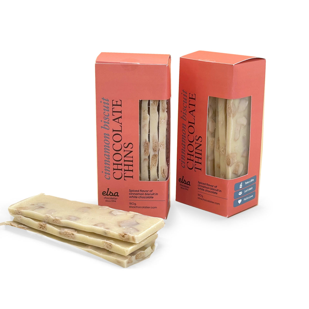 Cinnamon biscuit white chocolate thins stacked beside two coral-colored window boxes.