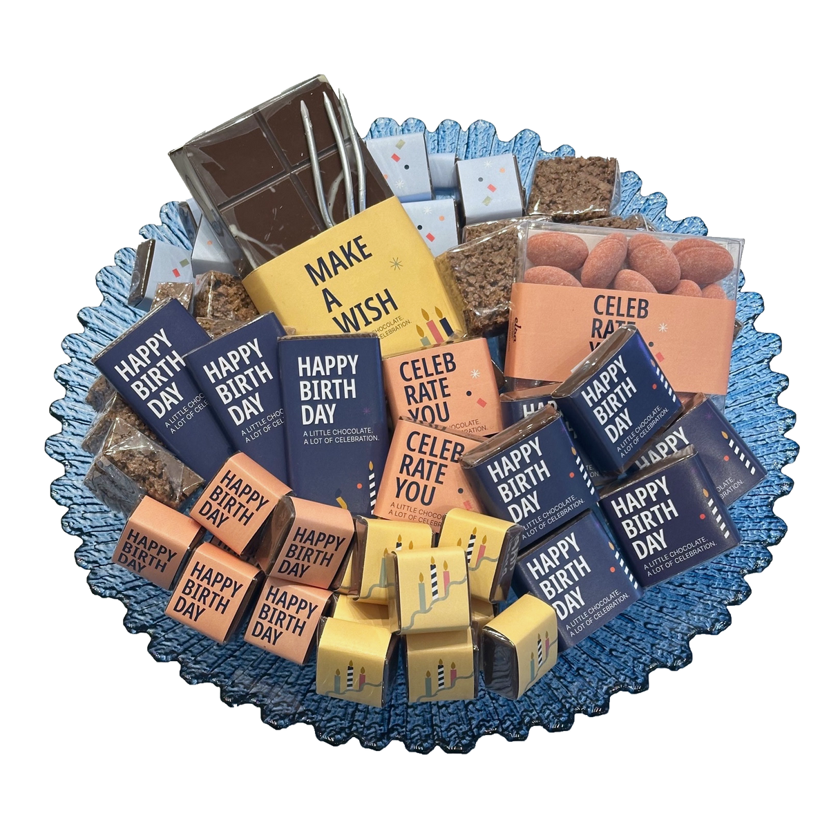 Overhead view of a blue scalloped glass bowl filled with colourful birthday-wrapped chocolates