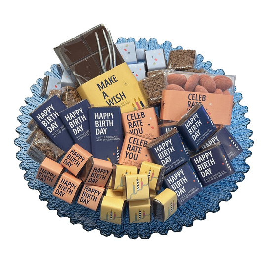 Overhead view of a blue scalloped glass bowl filled with colourful birthday-wrapped chocolates