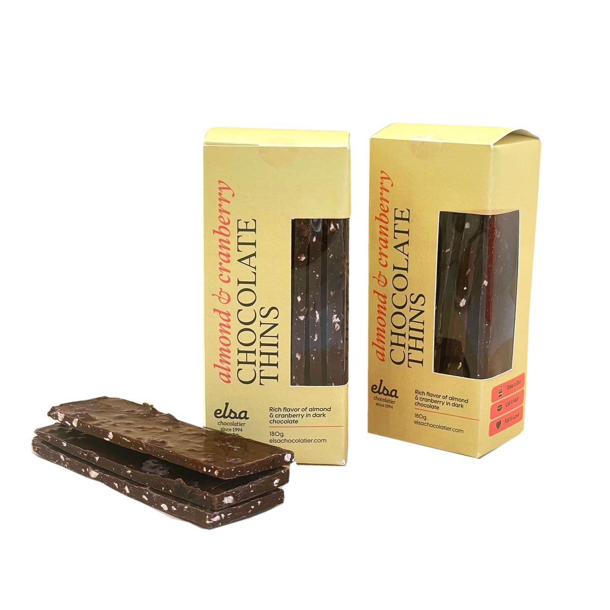 Almond and cranberry dark chocolate thins stacked beside two yellow boxes